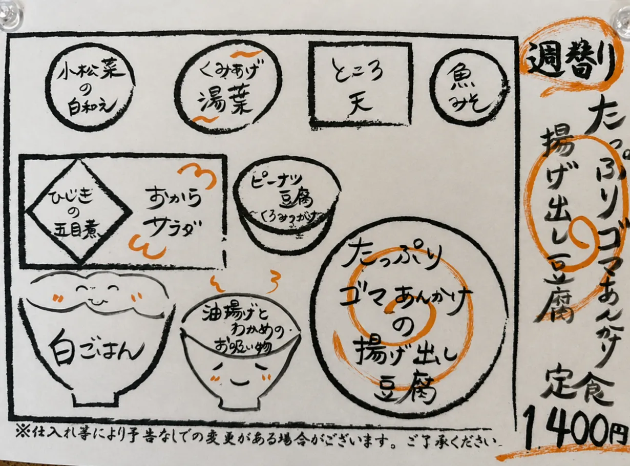 「たっぷりゴマあんかけの揚げ出し豆腐定食1,400円」と小鉢の内容が手書きで描かれた週替わりの案内